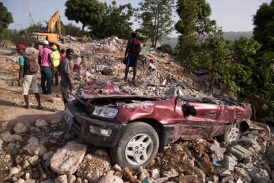 Varias personas permanecen cerca de un vehículo aplastado por la caída de un muro durante el terremoto del pasado 14 de agosto, hoy, en Marceline (Haití). El número de muertos fue de más de 2.200 personas.