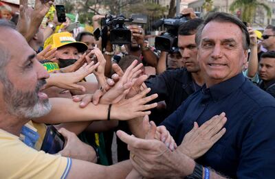 Brazil's President Jair Bolsonaro (R) is greeted by supporters after taking part in a motorcade rally as part of his re-election campaign, at Praca da Liberdade in Belo Horizonte, Minas Gerais State, Brazil, on August 24, 2022. (Photo by Douglas MAGNO / AFP)
