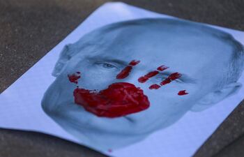 Un cartel que muestra una imagen del presidente ruso Vladimir Putin con una mano roja impresa durante una manifestación en apoyo de Ucrania en Santa Mónica, California.