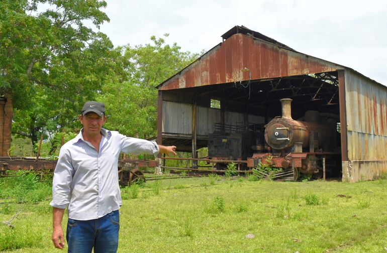 El exfuncionario de Fepasa Severiano González, actual casero de la exestación de San Salvador, señala las dos locomotoras que tiene el lugar, el cual se encuentra en total abandono de parte de las autoridades.