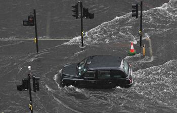 Un taxi londinense atraviesa el agua en una carretera inundada en el distrito de Nine Elms de Londres ayer, domingo.