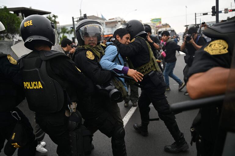 A supporter of Peruvian President Pedro Castillo struggles with the police to reach the Lima Prefecture, where Castillo is alleged to be, in Lima, on December 7, 2022. - Peru's President Pedro Castillo dissolved Congress on December 7, 2022, announced a curfew and said he will form an emergency government that will rule by decree, just hours before the legislature was due to debate a motion of impeachment against him. (Photo by ERNESTO BENAVIDES / AFP)
