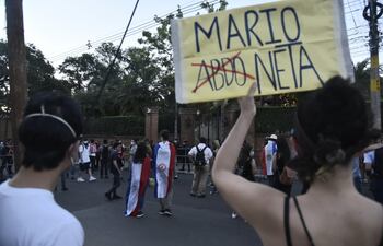 Una mujer sostiene un cartel que hace un juego con la combinación del nombre del presidente Mario Abdo y la palabra "marioneta", frente a la casa del expresidente Horacio Cartes.