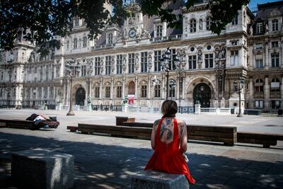 Una mujer se sienta al aire libre en un espacio público de París.