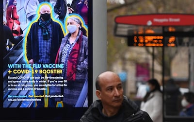 Un peatón camina próximo a un cartel del National Health Service (NHS) que promociona el refuerzo de la vacuna contra el Covid-19, así como la aplicación de la vacuna contra la gripe.