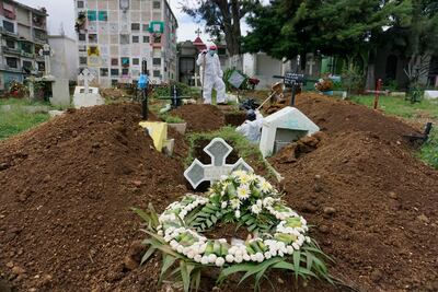 Sepultureros con trajes de bioseguridad cavan una tumba para enterrar el ataúd de una víctima de COVID-19 en el cementerio municipal de Mixco, en Mixco, a 20 km al oeste de la ciudad de Guatemala.