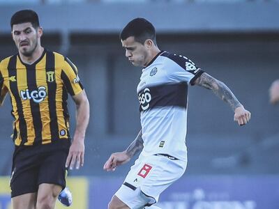 William Mendieta juega el balón ante la mirada de José Florentín, futbolista de Guaraní.