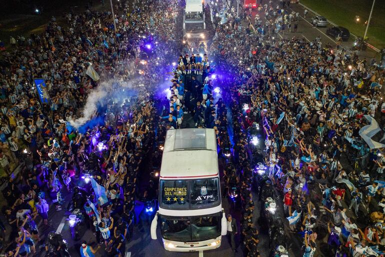 Los jugadores de la selección de Argentina a bordo del bus descapotable durante el recorrido hasta el predio de Ezeiza en compañía de miles y miles de argentinos, que recibieron al plantel en el Aeropuerto Internacional de Ezeiza después de la conquista del Mundial Qatar 2022. 