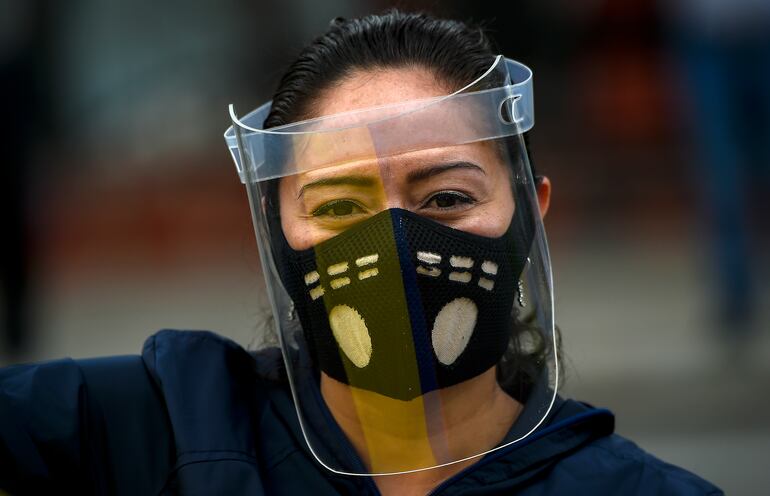 Una mujer se protege contra el coronavirus vistiendo un barbijo y un protector facial. Los tapabocas bien utilizados deben cubrir el mentón, la boca y la nariz.