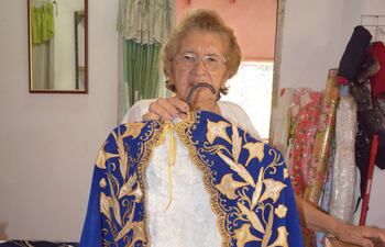 Doña Celina de las Nieves Moreno López muestra el vestido y la capa de la imagen de la Virgen María.