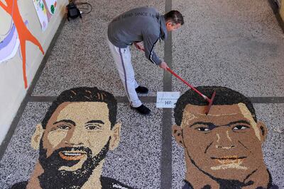 El artista kosovar Alkent Pozhegu tabaja en los últimos detalles de su mural hecho con granos y semillas, que retrata al ídolo argentino Lionel Messi y al francés Kylian Mbappe, en el pueblo de Gjakova.