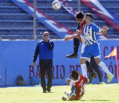 Los azulgranas Pablo Adorno y Bruno López (en el piso) salen al cruce del mediocampista del 12 de Octubre, Rubén Darío Ríos.