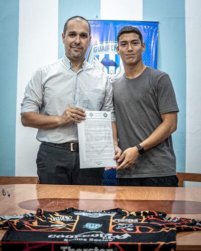 El presidente Luis Cáceres Smith sostiene el contrato junto a Édgar González.