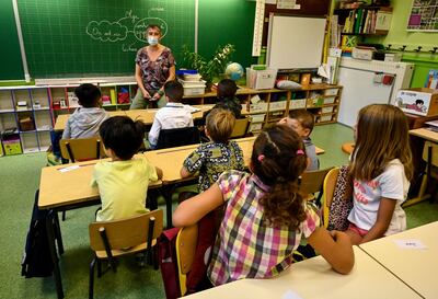 Los niños escuchan a un maestro con una máscara protectora durante una clase en la escuela primaria Jules Simon, en Montpellier, Francia.