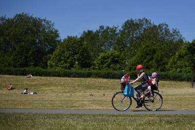 Una mujer en bicicleta pedalea llevando a su hija a través del parque Burgess, al sur de Londres.