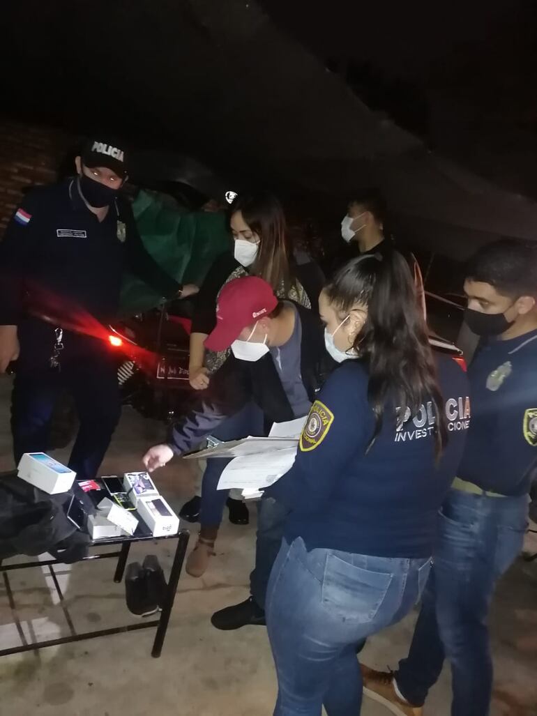 Los intervinientes verifican los celulares incautados durante el procedimiento. 