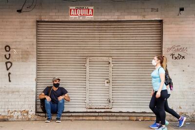 Dos personas con tapabocas caminan por una calle del microcentro asunceno, frente a un negocio en alquiler.