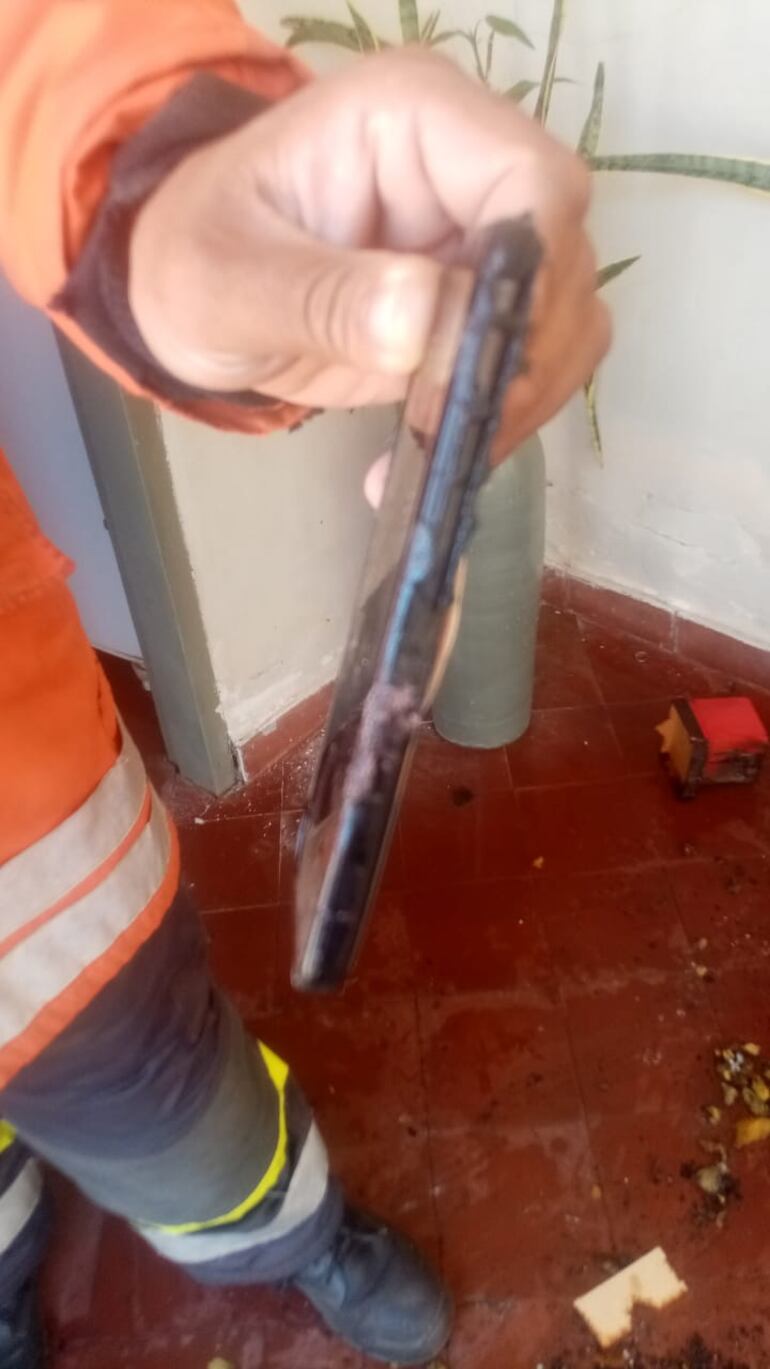Teléfono celular quedó muy averiado por el presunto recalentamiento por estar enchufado con un cargador dentro de la casa. (gentileza).