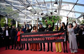 Miembros de la película “Crowra” protestando detrás de una pancarta “El futuro de las tierras indigenas en Brasil está bajo amenaza” en la alfombra roja del Festival de Cine de Cannes