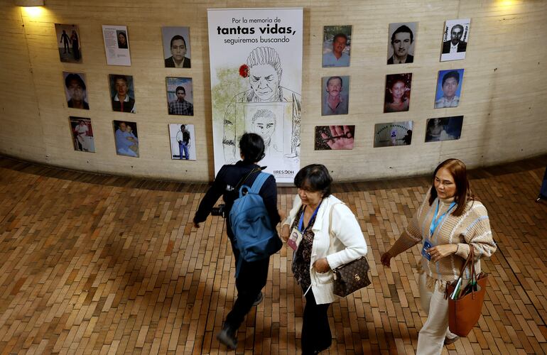Asistentes a la biblioteca Virgilio Barco observan una exposición con los rostros de las víctimas de secuestro, durante el proceso conocido como el "Caso 01" de la JEP, en Bogotá (Colombia).