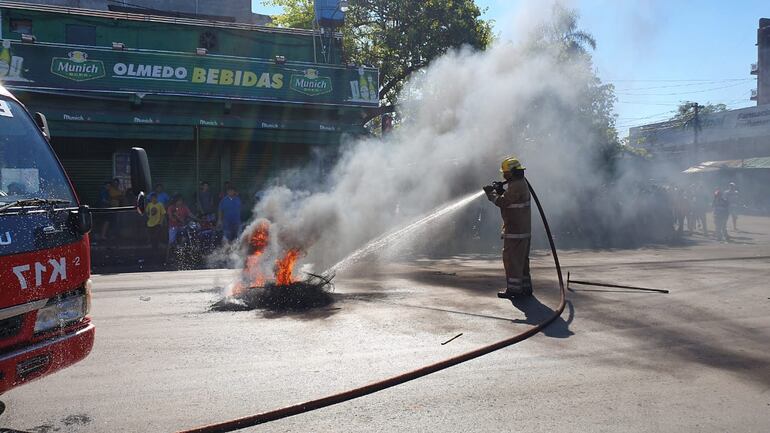 Un voluntario sofoca la quema de cubiertas para despejar la pista.