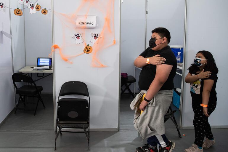 Dos niños caminan por un centro de vacunación contra el Covid-19 decorado con motivos de Halloween hoy, en Santiago (Chile). 