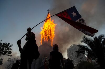 Un manifestante con una bandera chilena frente a una iglesia en llamas en Santiago, el pasado domingo.