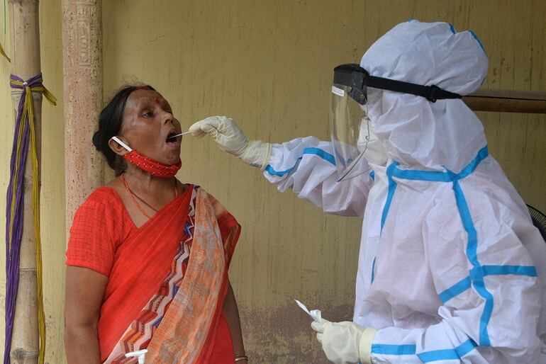 Un trabajador médico toma una muestra de una mujer para una prueba de covid-19 en un centro de salud en Siliguri, India, este lunes.
