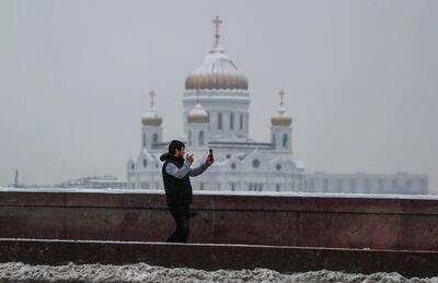 Un hombre sostiene su teléfono móvil frente a la catedral de Cristo Salvador, en Moscú.