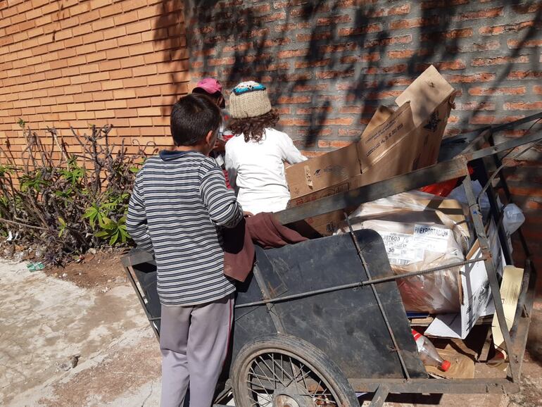 Niños recolectando cartón con su mamá