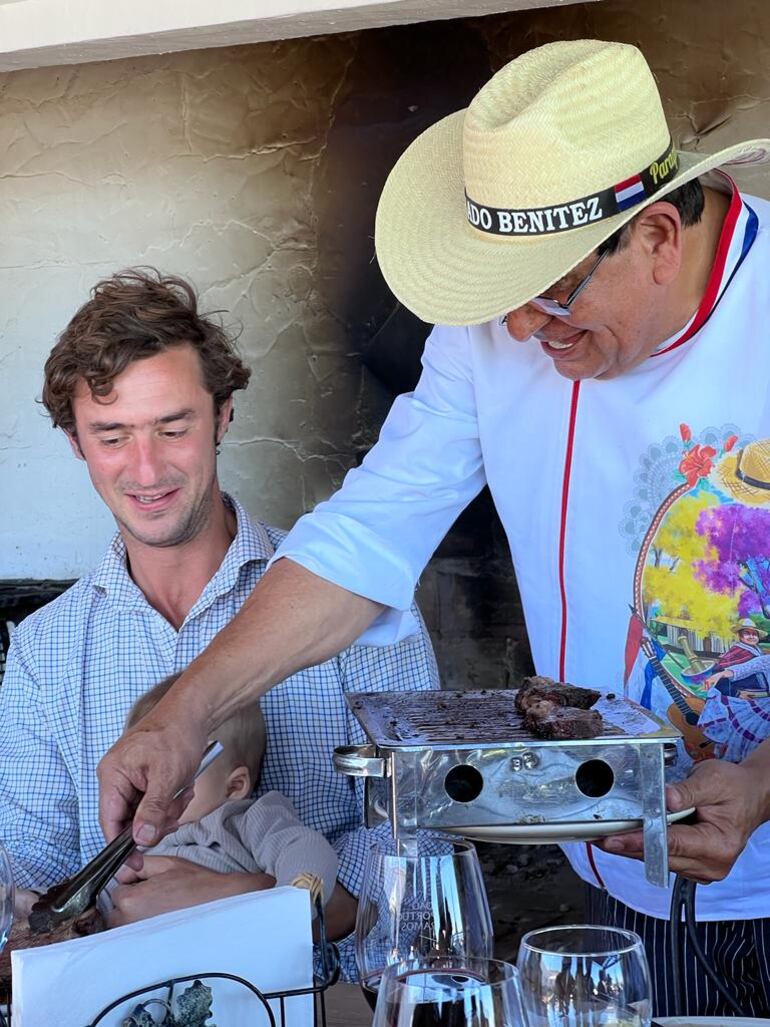 Don Benjamín Benítez sirviendo carne paraguaya a un invitado especial del almuerzo organizado por la Embajada del Paraguay en Portugal. (Gentileza)