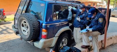 Agentes de Criminalística verifican el interior de la camioneta Nissan Patrol abandonada por los maleantes.