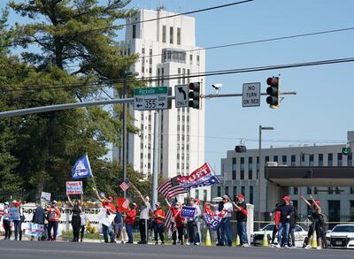 Los partidarios del presidente de los Estados Unidos, Donald Trump, sostienen carteles y banderas el 4 de octubre de 2020 fuera del Centro Médico Walter Reed en Bethesda, Maryland.