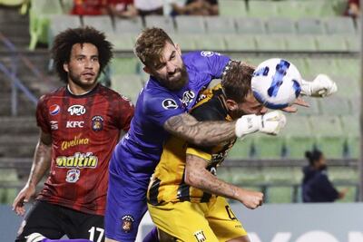 El arquero Alain Baroja (c) de Caracas disputa el balón con Juan Bautista Cascini (d) de The Strongest, durante un partido del Grupo B de la Copa Libertadores, disputado anoche en el Estadio Olímpico, en Caracas (Venezuela).