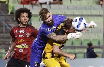 El arquero Alain Baroja (c) de Caracas disputa el balón con Juan Bautista Cascini (d) de The Strongest, durante un partido del Grupo B de la Copa Libertadores, disputado anoche en el Estadio Olímpico, en Caracas (Venezuela).