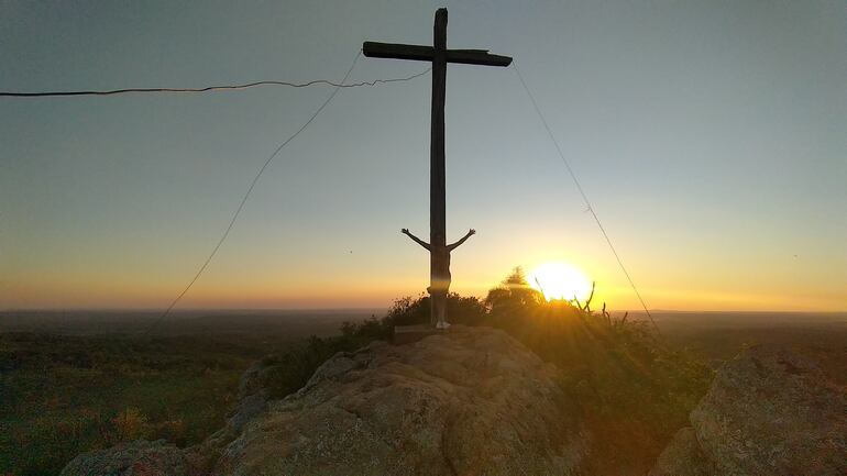 Una visitante del Cerro San Joaquín, posando con la cruz y con el fondo de la puesta del sol del atardecer.