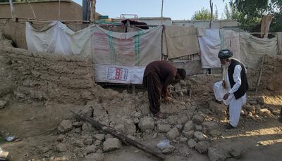 Vecinos de la localidad de Harnai, Pakistán, recogen escombros de una vivienda parcialmente derrumbada.