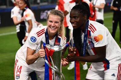 La delantera noruega Ada Hegerberg (i) y la defensa francesa Griedge Mbock Bathy posan sonrientes con el trofeo de la Champions League, que el Lyon francés conquistó ayer tras superar en la final al Barcelona.
