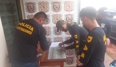 Policías de Investigaciones y de Antisecuestro cuentan los billetes de dólares recuperados del poder del adolescente de 16 años en Capitán Bado.