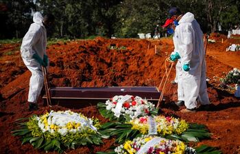 Unos trabajadores colocan un ataúd dentro de una tumba en el cementerio Vila Formosa, el 24 de marzo de 2021, en Sao Paulo (Brasil).
