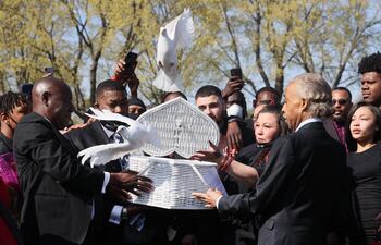 Katie Wright, madre de Daunte Wright, flanqueada por el abogado de derechos humanos Ben Crumpy y el reverendo Al Sharpton y familiares libera palomas en una breve ceremonia en el cementerio Lakewood.