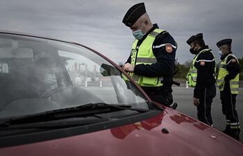 Un oficial de la gendarmería francesa controla a un conductor en una salida de la autopista A10 que une París y Burdeos, durante el cierre destinado a frenar la propagación de la pandemia Covid-19 en Virsac, suroeste de Francia, el 9 de abril de 2021.