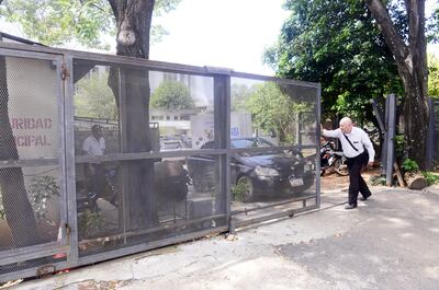 Una persona  empuja el pesado portón que debía abrirse automáticamente con la llegada de cada concejal.