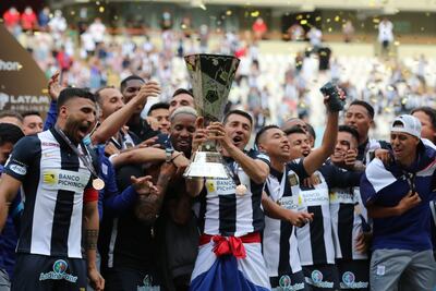 Edgar Benítez levanta el trofeo de campeón rodeado de sus compañeros.