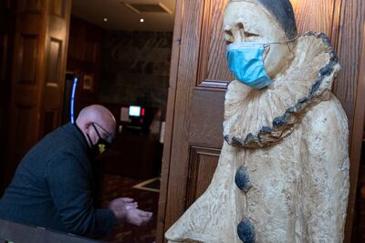 Un hombre se lava las manos junto a una estatua con mascarilla a la entrada de un bar en Leigh, en el noroeste de Inglaterra.