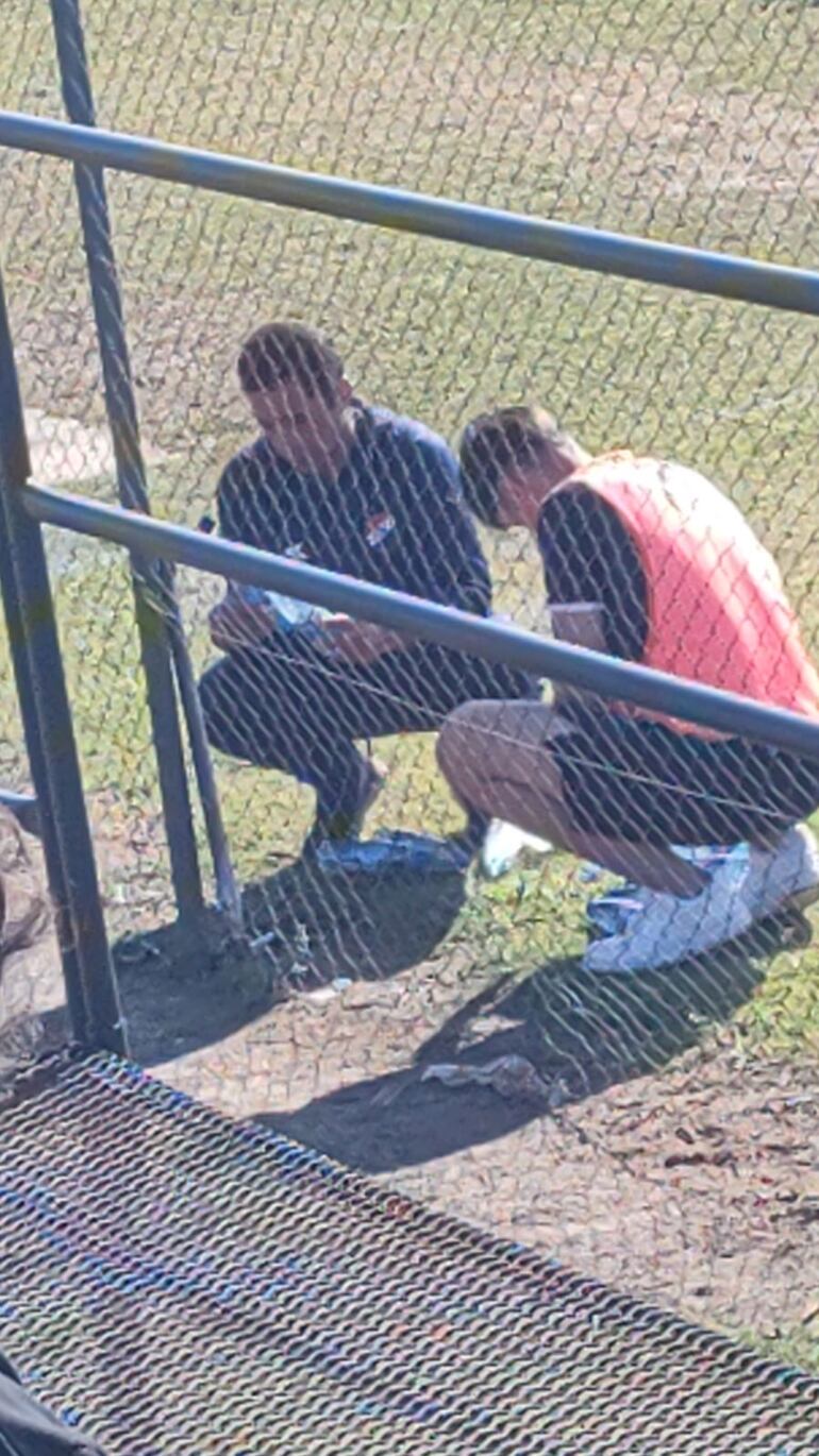 Uno de los integrantes del cuerpo técnico de la reserva de Nacional y uno de los jugadores del plantel, mientras cargaban agua de la canilla.