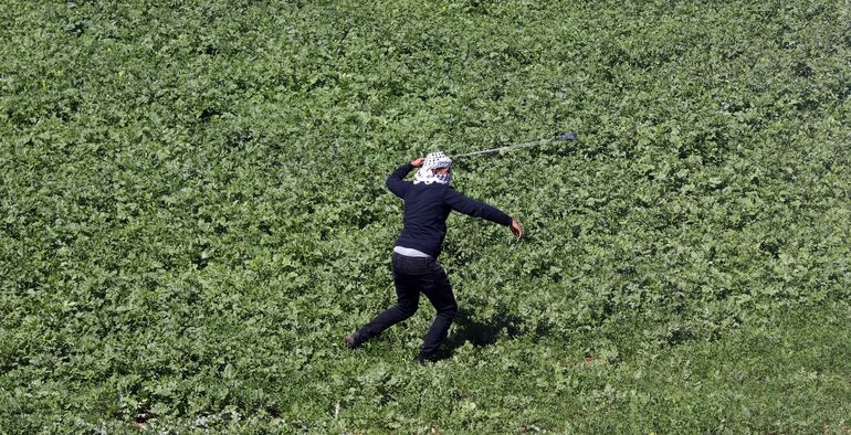 Un manifestante palestino lanza piedras a soldados israelíes durante una protesta cerca de Nablus.
