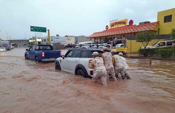 MEX1280. NOGALES (MÉXICO), 13/08/2022.- Soldados del Ejército Mexicano auxilian hoy a un conductor atrapado en una inundación producida por fuertes lluvias en la ciudad de Nogales, estado de Sonora (México). Dos niñas de 6 y 10 años y una mujer adulta murieron ahogadas este sábado al ser arrastradas por el caudal provocado por una intensa una tormenta, que además generó inundaciones y arroyos en las calles principales de la ciudad de Nogales, en el estado de Sonora, fronteriza con Estados Unidos. EFE/Daniel Sánchez