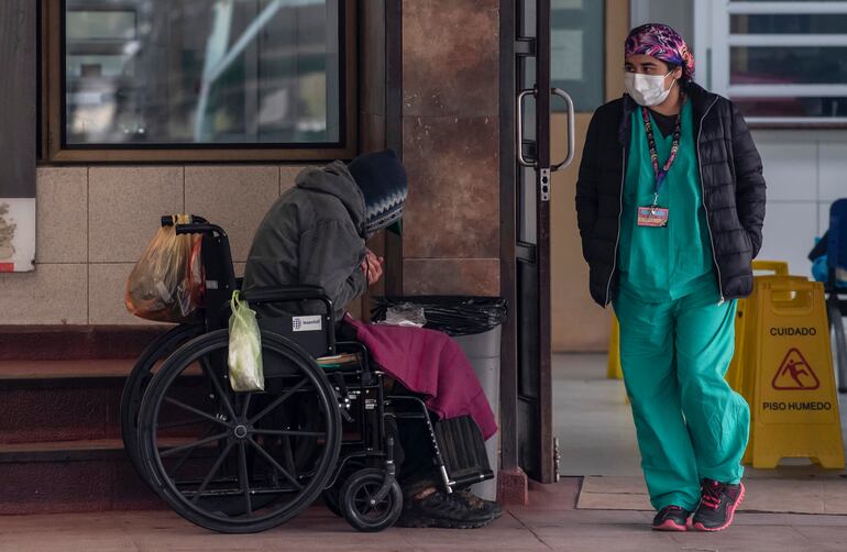 Una persona indigente espera fuera del área de urgencias del hospital San José de Santiago.