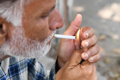 Un hombre enciende un cigarrillo.